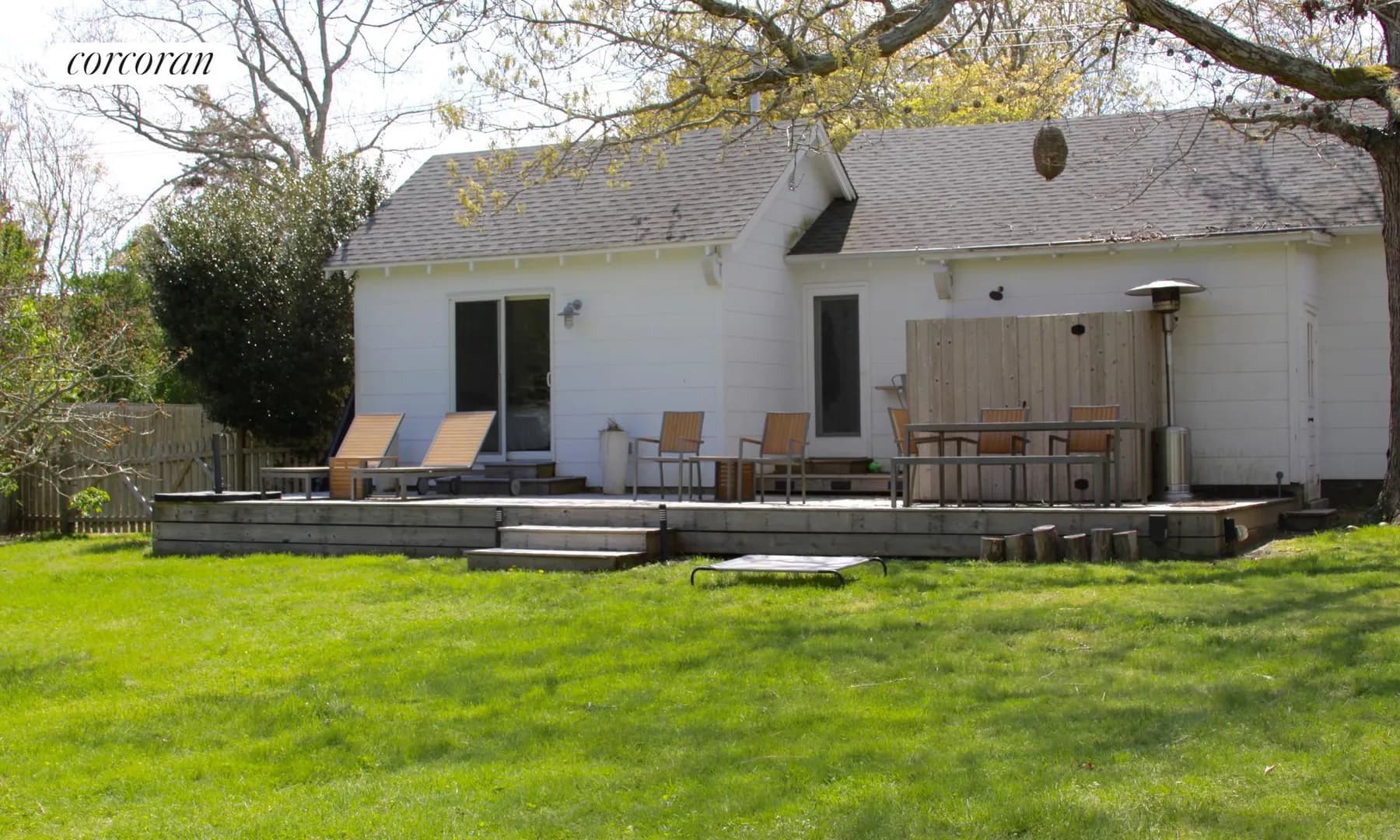 Full-length back deck with lounge chairs and dining area overlooking green lawn