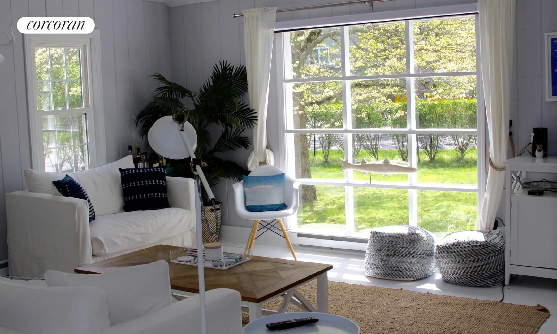Sunny living room with white furniture and large window overlooking the yard