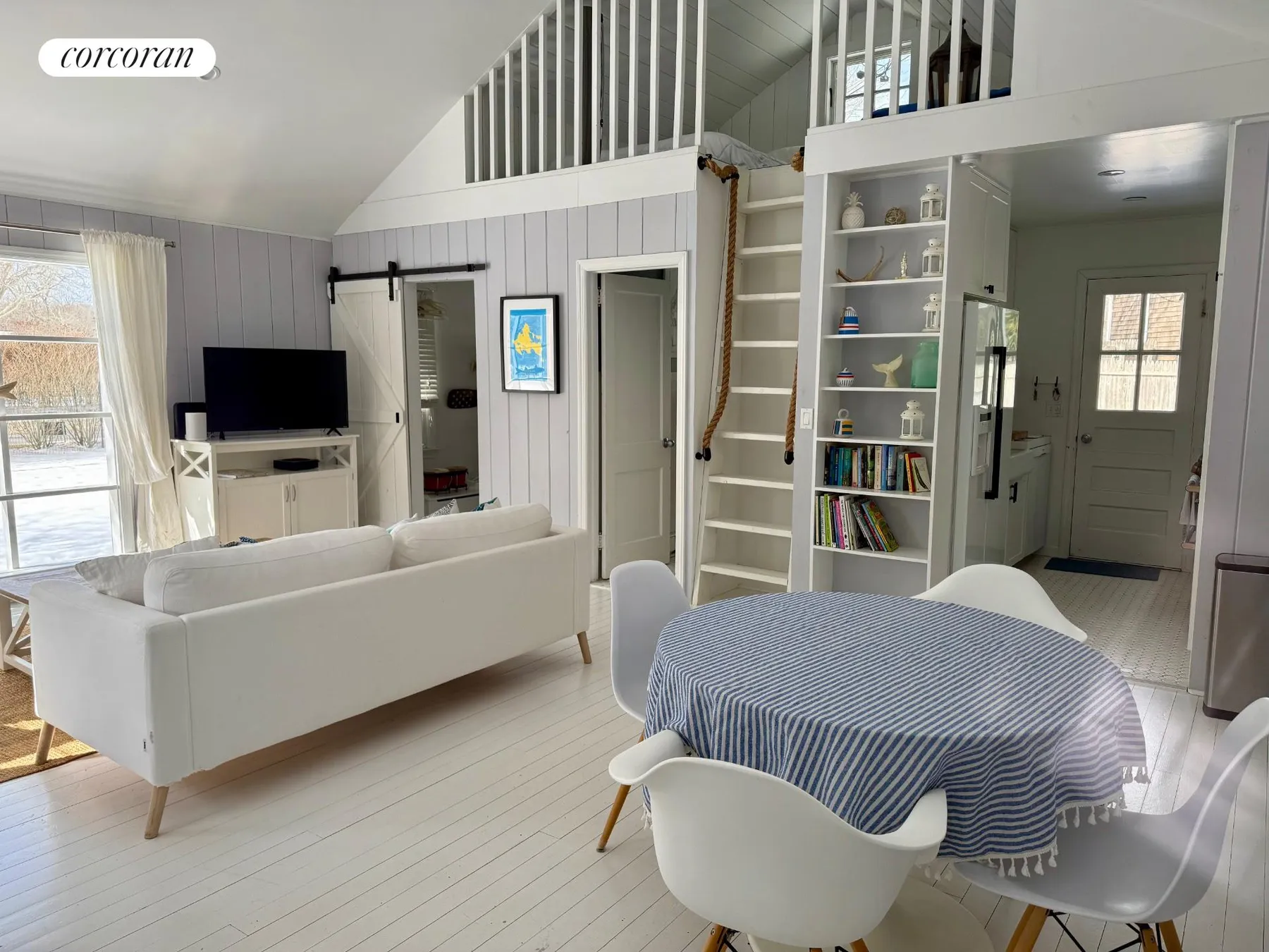 Open floor plan showing loft ladder, bookshelves, and dining area