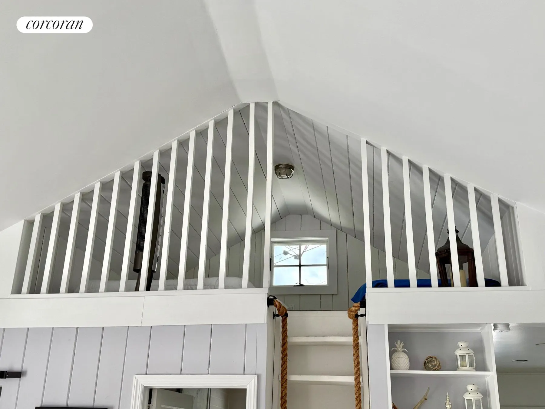 View up to the vaulted loft with white railings and ladder access