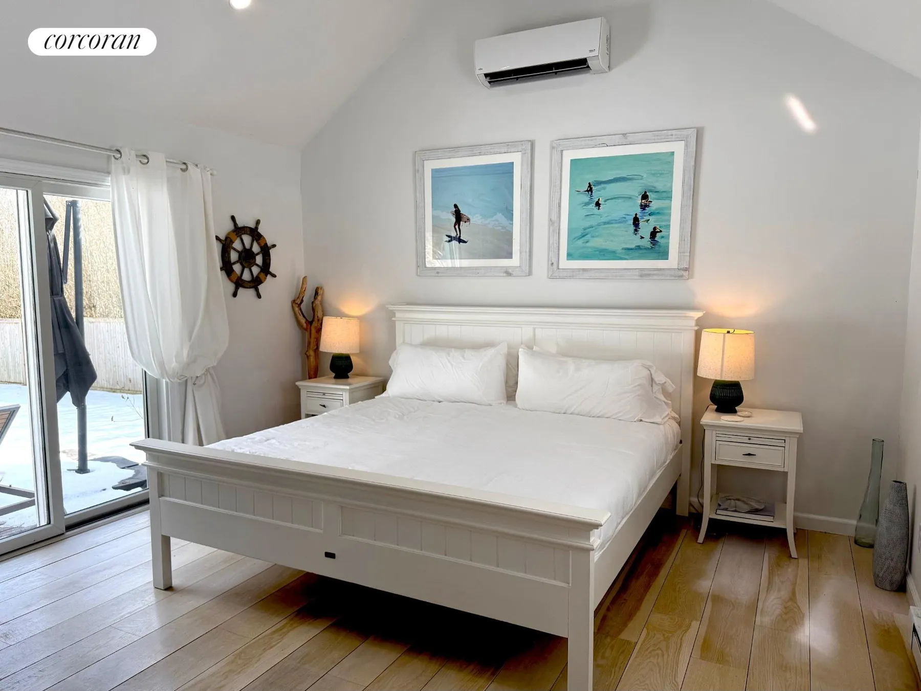 Master bedroom with king bed, beach art, and sliding doors to deck