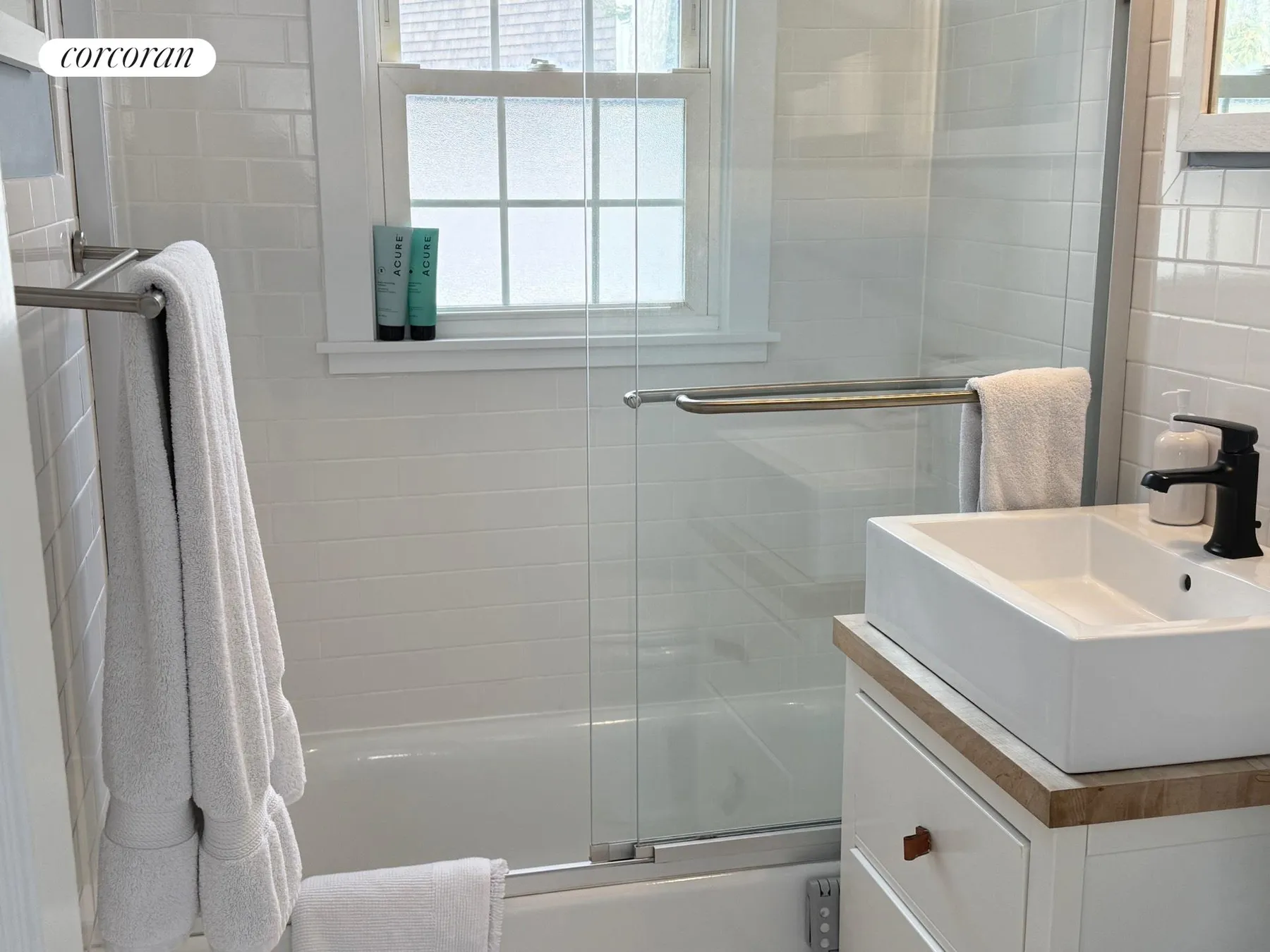 Bathroom with white subway tile, glass shower door, and modern vanity