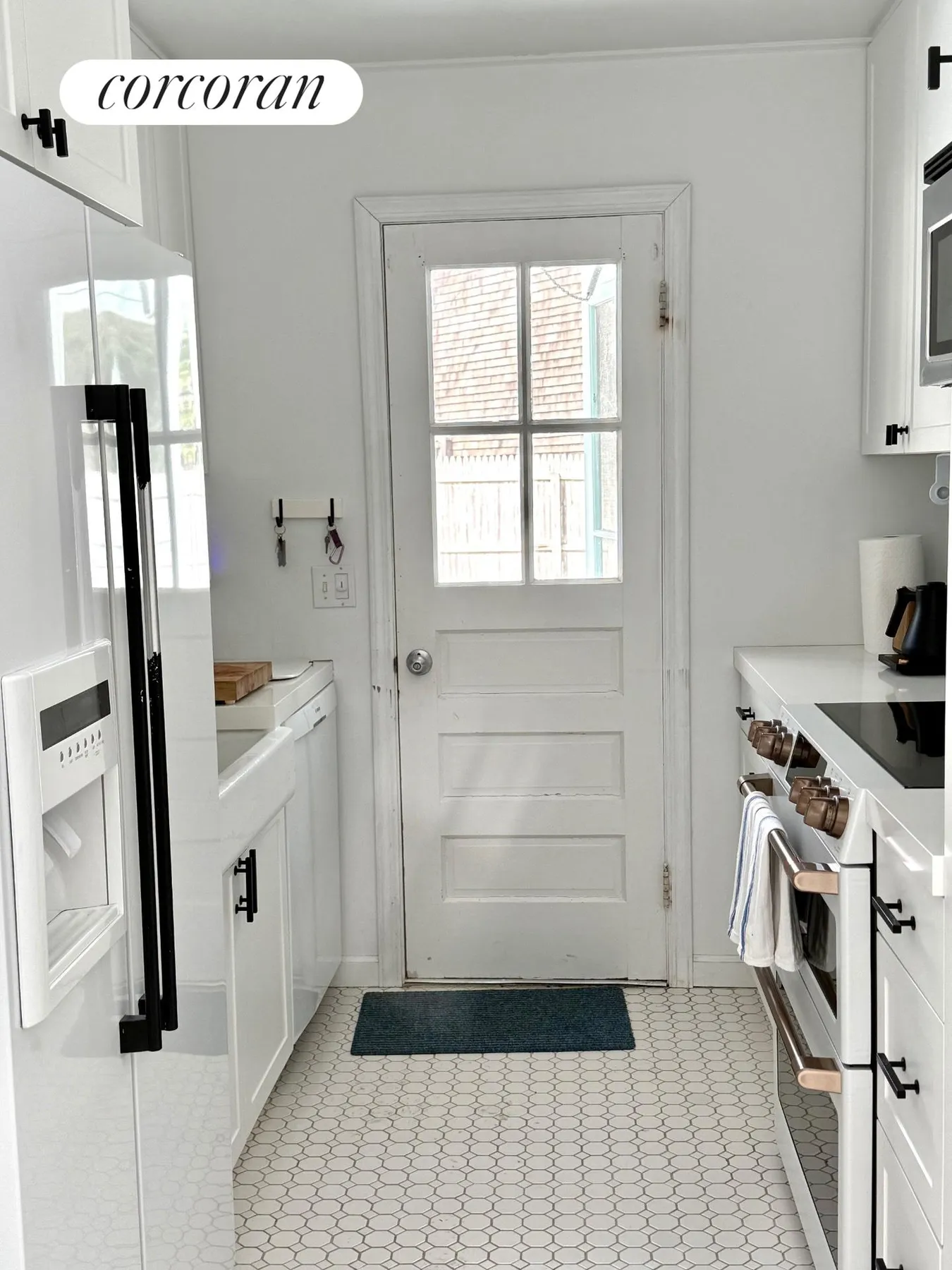 Renovated galley kitchen with white cabinets, hex tile floor, and black hardware