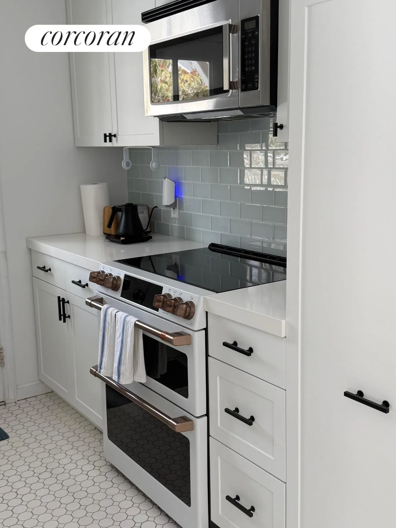 Kitchen with induction stove, microwave, and glass tile backsplash