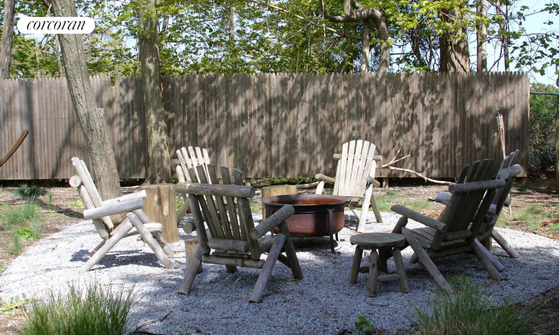 Secluded fire pit area with Adirondack chairs on gravel